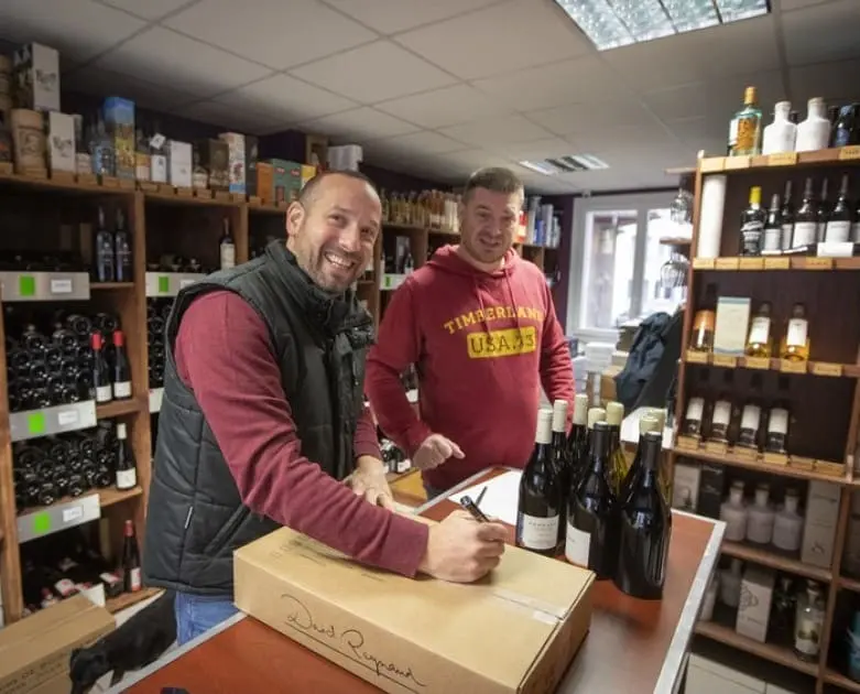 L'équipe de la boutique As du Vin à Dijon préparant avec soin une commande de vin pour une expédition.