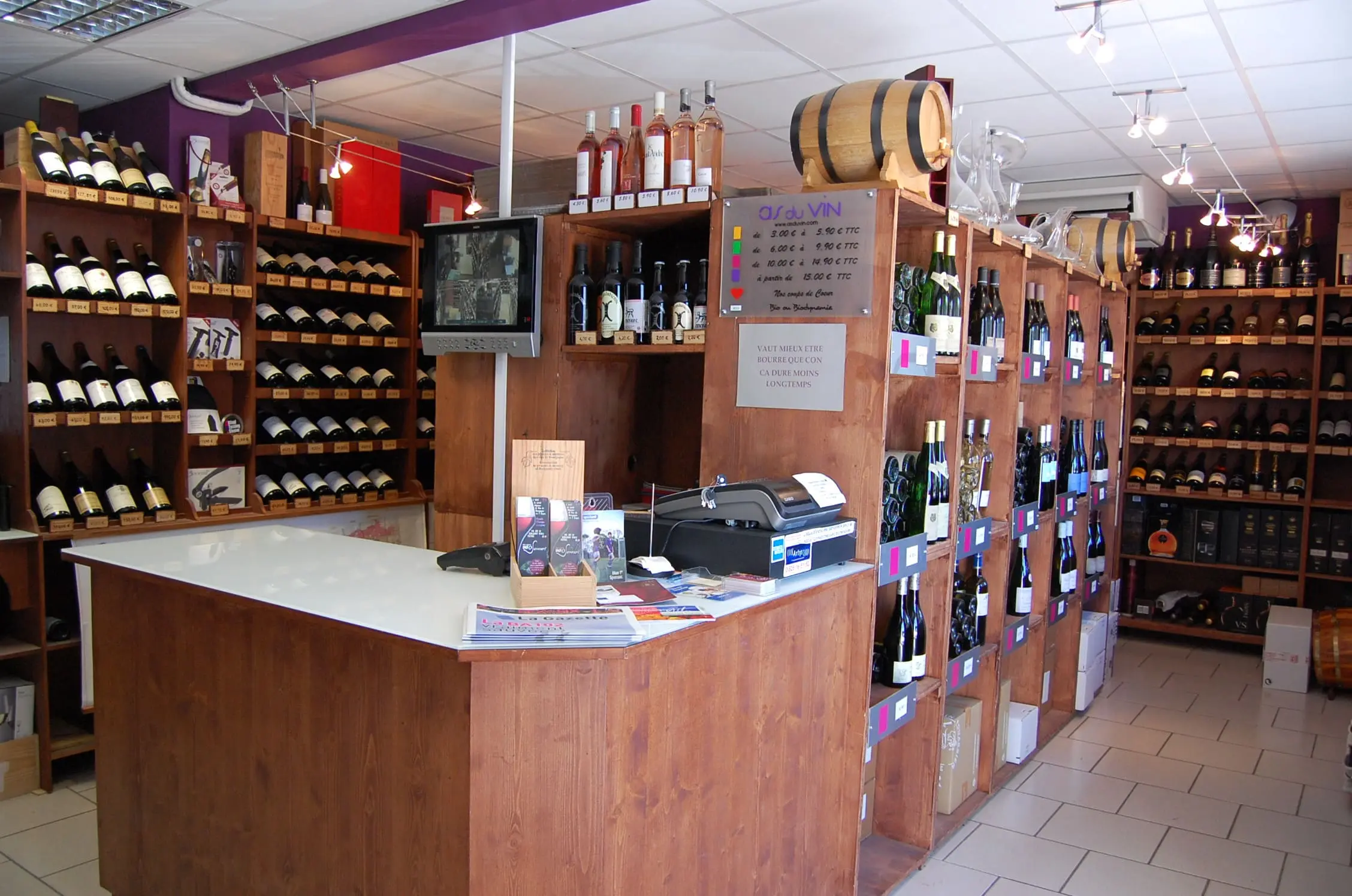 Intérieur de la cave à vins As du Vin à Dijon, présentant une large sélection de crus de Bourgogne et spiritueux sur des étagères en bois.